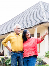 happy elderly couple in front of their house